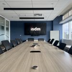 ISDM large meeting room with logo on screen above a large conference table and chairs