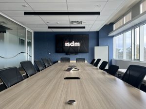 ISDM large meeting room with logo on screen above a large conference table and chairs 